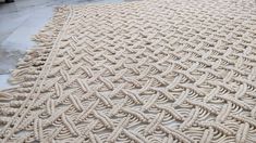 a large white rug on the ground with ropes and knots in it's center