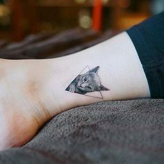 a person's foot with a small tattoo of a cat on it and an arrow in the middle