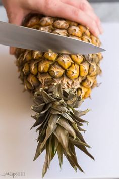 a person cutting up a pineapple with a knife