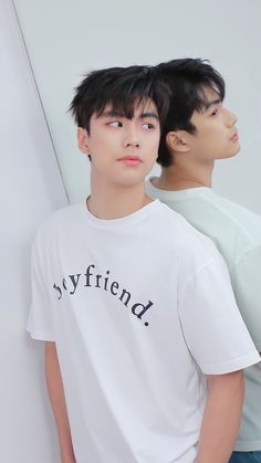 two young men standing next to each other in front of a white wall with the word boyfriend written on it