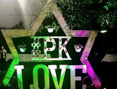 a green sign that says pk love with bicycles in front of trees and people