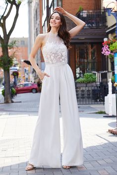 a woman standing on the sidewalk wearing a white jumpsuit