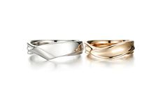 two gold and silver rings with different designs on them, one in the shape of a wave