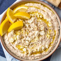 a bowl filled with hummus and sliced lemons