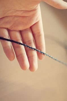 a hand holding a piece of string on top of a table