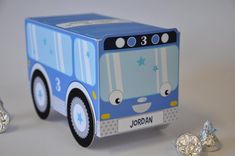 a blue train shaped box next to some silver foiled candies on a white surface