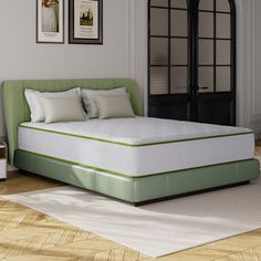 a green bed frame with white pillows on it in front of a black door and wooden floor