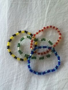 four beaded bracelets sitting on top of a white sheet