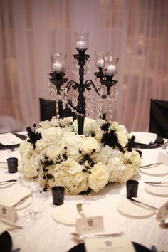 the centerpiece is made up of white flowers and black candlesticks, along with silverware