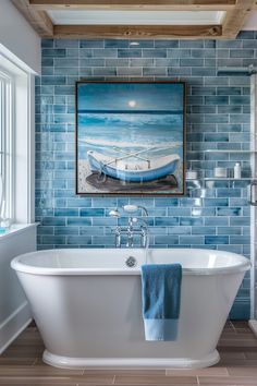 a white bath tub sitting next to a window in a bathroom under a painting on the wall