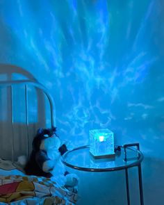 a teddy bear sitting on a bed in front of a blue light