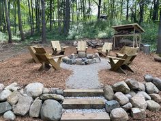 there is a fire pit in the middle of some rocks and gravel with chairs around it