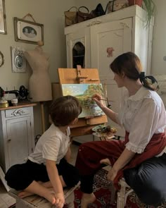 a woman and two children sitting in front of an easel