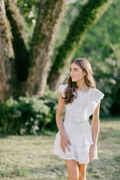 a young woman in a white dress is posing for the camera with her hands on her hips