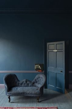 a chair sitting in front of a blue wall with a red rug on the floor