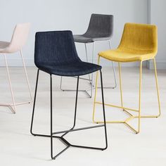 four different colored barstools in an empty room