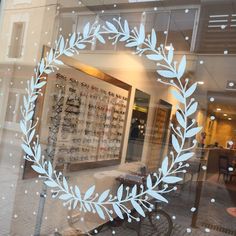 a store front window with a white wreath on it's glass and people walking by