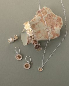 an assortment of jewelry sitting on top of a table next to a rock and stone