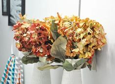 three white vases with flowers in them