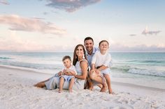 a family poses on the beach at sunset for a photo session with their two children