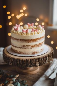 a cake with white frosting and pink bows on top sitting on a wooden platter