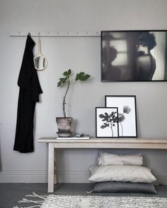 a white table with some pictures on the wall and a potted plant next to it