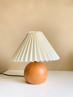 a wooden table lamp with a white shade on it's base and an apple underneath