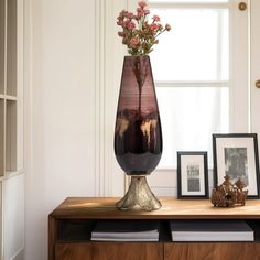 there is a vase with flowers in it sitting on a table next to two pictures