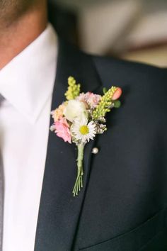 a man in a suit and tie wearing a boutonniere with flowers on it