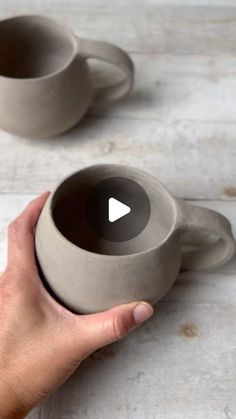 a hand holding a cup with two cups in the middle and one on the other side