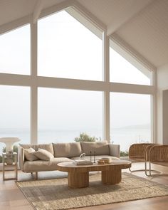 a living room filled with lots of furniture next to large windows on top of a wooden floor