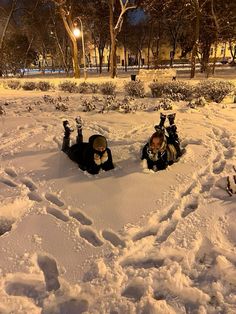 two people laying in the snow with skis on their feet