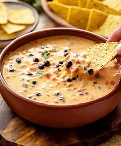 a hand dipping a tortilla chip into a bowl of quesadilla soup