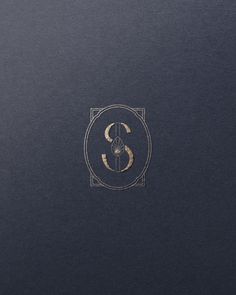 the letter s is inscribed in gold on a black paper with a golden border around it