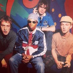 three young men sitting next to each other in front of a colorful wall