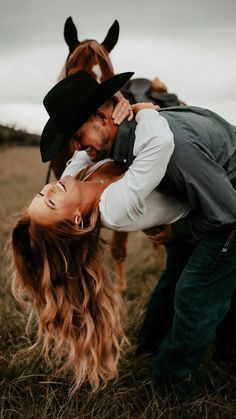 a man and woman kissing in front of a horse on a field with long hair