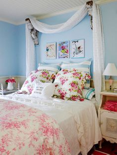 a bedroom with blue walls and white bedding, pink flowers on the comforter