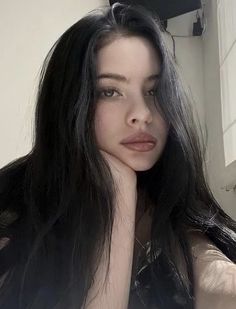 a woman with long black hair is taking a selfie