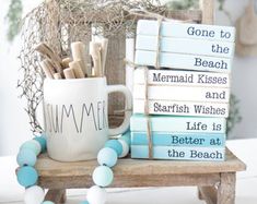 a stack of books sitting on top of a wooden chair next to a mug filled with sand