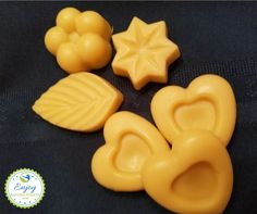 four yellow plastic objects with leaves and stars in them on a black surface, one is shaped like an elephant