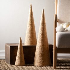 three small cones are sitting on the floor next to a chair and teddy bear in a basket