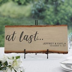 a wooden sign sitting on top of a table next to plates and silver utensils