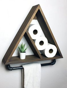 a triangle shaped shelf with toilet paper and plants in it on the wall next to two rolls of toilet paper