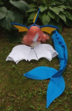 a doll is laying on the ground next to a blue and white batwing costume