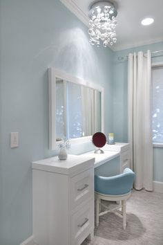 a blue and white bedroom with a vanity, chair and window