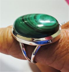 "Green malachite ring is a rare top quality natural bull's eye polished oval malachite gemstone ring in solid sterling silver ring size 7. Green malachite gem is a polished oval cabochon with Its perfect bulls eye formation in this best quality malachite gemstone. The oval malachite gemstone is approximate 18mm x 22mm in size. Solid sterling green malachite gemstone ring is size 7 and stamped \"925\" for solid sterling silver inside the band. Malachite Properties: Malachite is often called the \ Oval Malachite Emerald Ring, Malachite Properties, Handmade Malachite Ring, Green Malachite Rings With Polished Finish, Luxury Round Malachite Jewelry, Round Malachite Gemstone Jewelry, Silver Round Malachite Jewelry, Green Malachite Spiritual Jewelry, Malachite Ring