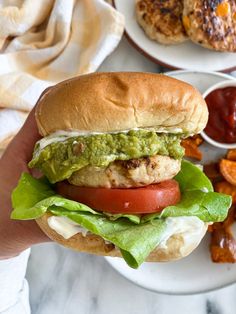 a chicken sandwich with lettuce, tomato and guacamole on it