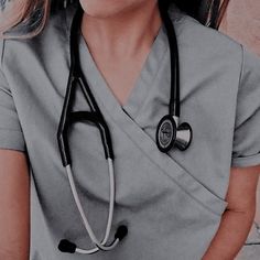 a woman in grey scrubs with a stethoscope on her neck