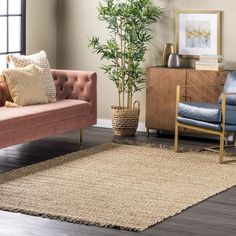 a living room with a pink couch, chair and potted plant in the corner