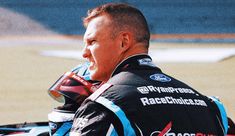 a man sitting on top of a motorcycle wearing a racing suit and holding his helmet